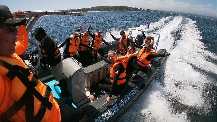 The Offshore Adventures boat at speed with guests in orange life jackets
